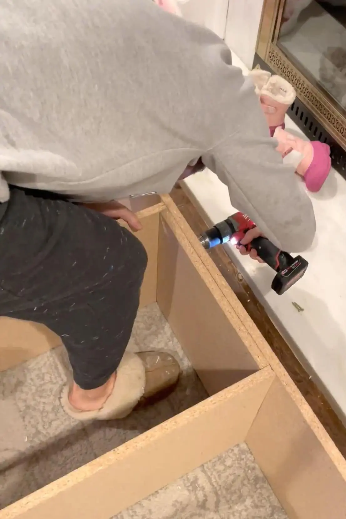 Using a power drill to secure MDF panels for a DIY storage unit, ensuring a strong and stable construction.